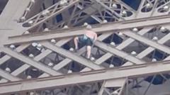 Man seen climbing Eiffel Tower above Olympic rings